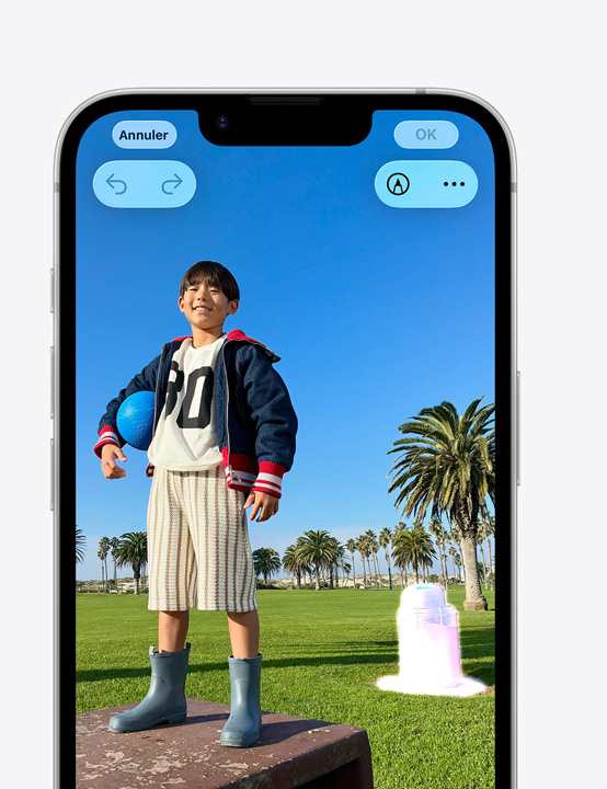 Écran d’iPhone, photo d’une personne souriante devant un parc, montrant comment supprimer une poubelle à l’arrière-plan avec l’outil Correction