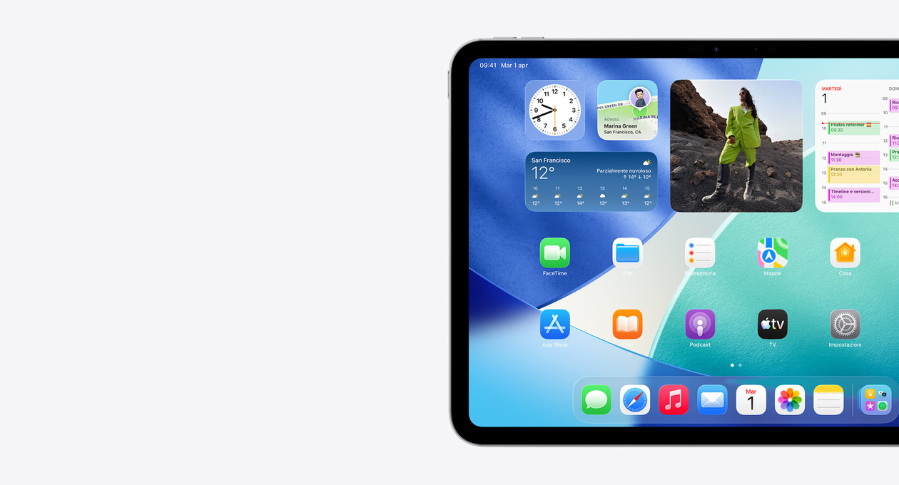 Un iPad in orizzontale, parte sinistra dello schermo, schermata Home con widget tra cui un orologio traslucido che mostra l’effetto Liquid Glass, l’app Dov’è, il widget Meteo, due file di app più piccole e il Dock