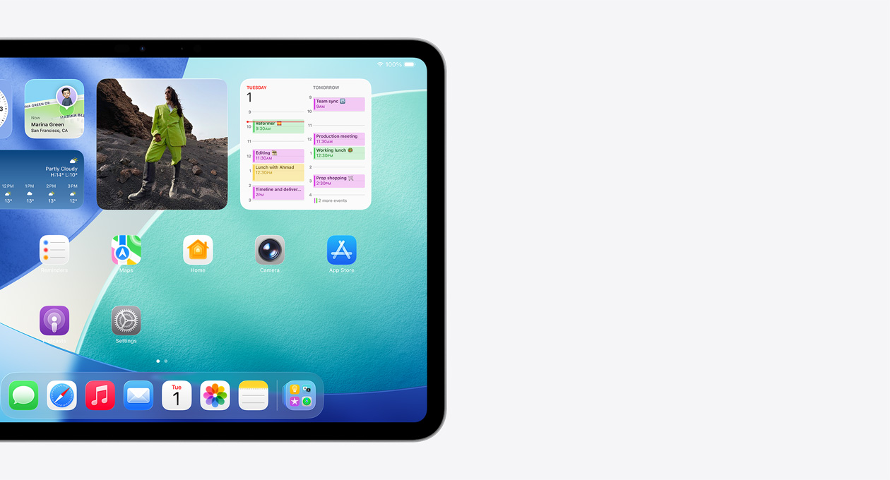 iPad في الوضع الأفقي، ويظهر الجانب الأيسر من الشاشة فقط، حيث أن الشاشة الرئيسية تتضمن الأدوات المكدسة بما فيها الساعة الشفافة التي تعرض تأثير Liquid Glass، وتطبيق تحديد الموقع، وأداة الطقس، وصفين من التطبيقات الأصغر، وشريط الأيقونات