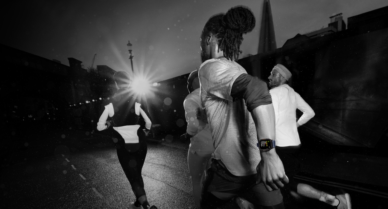 Four people running through an urban setting. One wearing Apple Watch