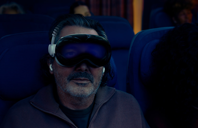 Eine Person sitzt in einem Flugzeug und trägt eine Apple Vision Pro mit einem Dual Band aus Strickgewebe