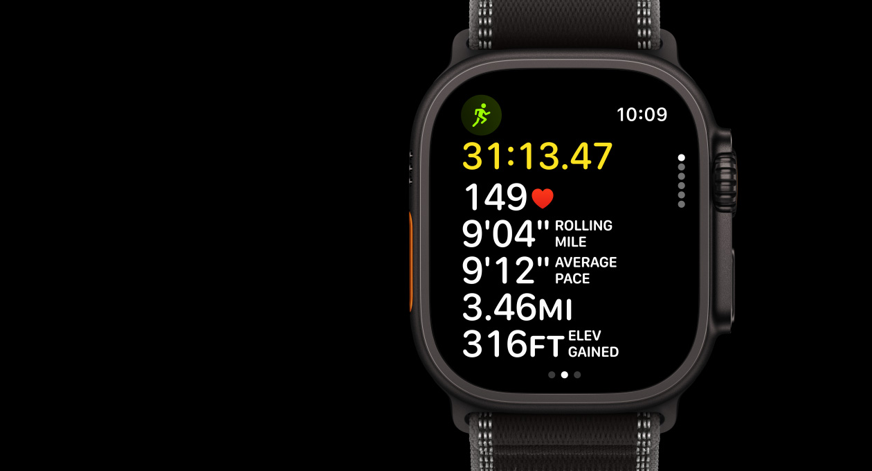 Apple Watch Ultra 3 com caixa em titânio preto, app Treino com Corrida (ar livre), botão Ação no lado esquerdo, Digital Crown e botão lateral no lado direito, bracelete Loop Trail preto/carvão