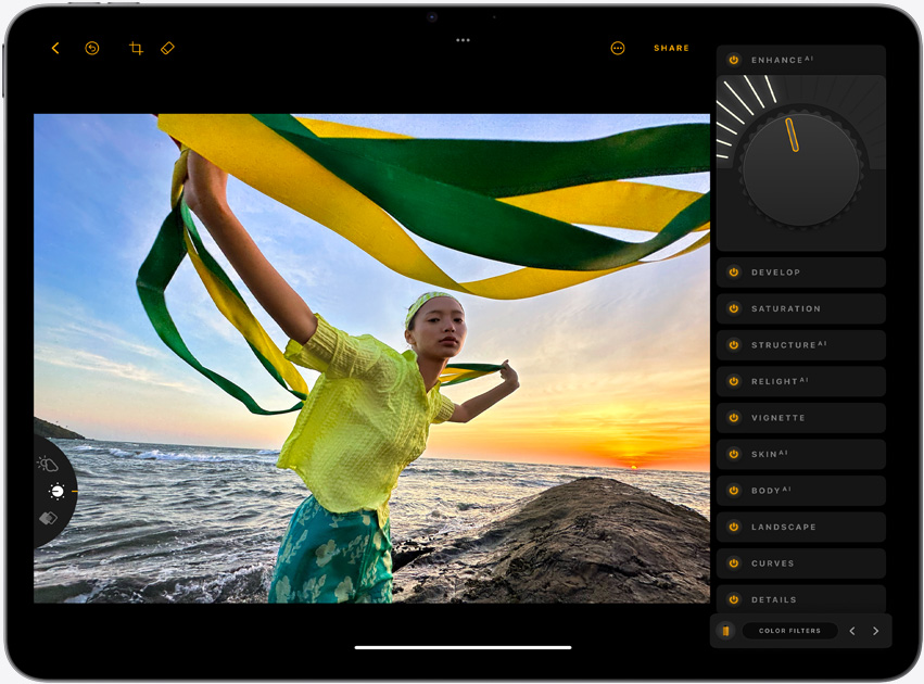 iPad Air, landscape orientation, screen displays a photograph of a girl holding yellow and green strands, standing in front of a sunset over the ocean