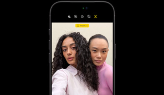 iPhone 18 Pro i sort vist forfra, der viser to personer med funktionen til registrering af ansigtsbevægelser og demonstrerer centreringsfunktionen i forsidekameraet