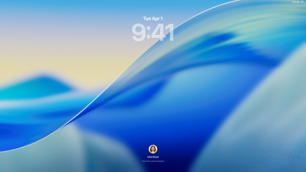 Vista frontal de três modelos Mac: MacBook Pro de 16 polegadas prateado à esquerda, com a app Telefone no ecrã a mostrar os contactos recentes, iMac de 24 polegadas azul ao centro, com a onda do papel de parede do macOS Tahoe no ecrã e MacBook Air de 13 polegadas meia‑noite à direita, com ecrã a mostrar uma pesquisa do Spotlight sobreposta na secretária com versões Liquid Glass da Dock e vários widgets como Calendário, Relógio e Meteorologia