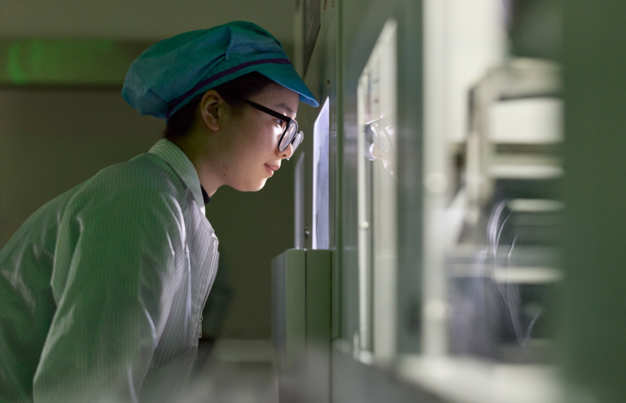 An employee in full-coverage work suit and eye wear observes Apple Watch assembly